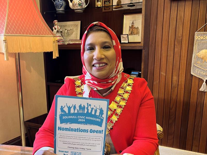 The Mayor of Solihull holding a Solihull Civic Honours awards flyer