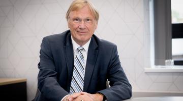 Councillor Ian Courts sits at a desk. 