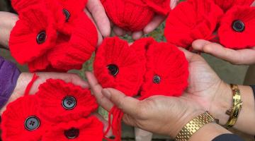 Hands holding examples of knitted and crocheted poppies