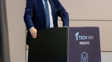 Man in a suit at a lectern with Birmingham Tech Week logo