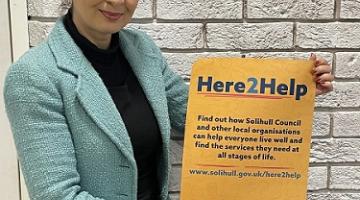 Image of Councillor Qais holding a Here2Help poster  