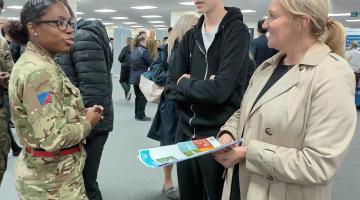 A young person and his parent are learning about apprenticeships from an exhibitor, the British Army