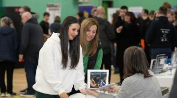 A young person and her parent learning about apprenticeships at a previous apprenticeship show