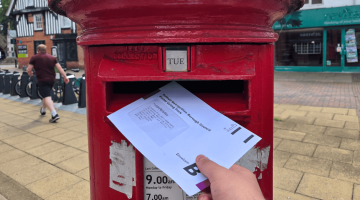 A person putting a postal vote into the letterbox