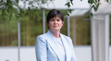 Cllr Karen Grinsell in a light blue jacket and top in front of a building
