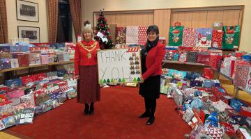 cllr Grinsell and the mayor stand with presents in the civic suite