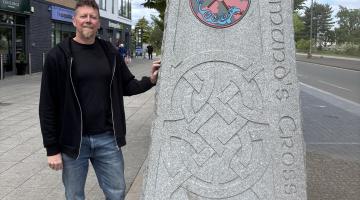Neil Roberts standing next to a stone sign with the text Chelmund's Cross