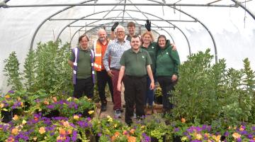 Service users at Newlands Bishop Farm stand in the polytunnel, with Cllr Ken Hawkins and representatives from Veolia and Newlands Bishop Farm