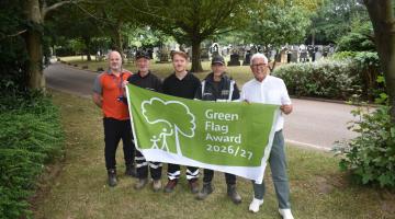 Staff from Veolia with Cllr Ken Hawkins hold the Green Flag banner in the cemetery
