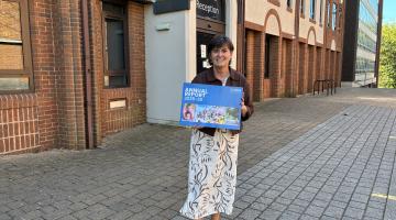karen grinsell outside of the council house holding an annual report photo