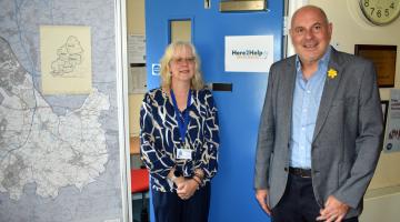 Kerry Turner and Cllr Tony Dicicco stood next to a Here2Help Advice Service sign