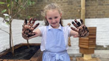 A school girl with muddy hands, promoting the Veolia Orchard scheme