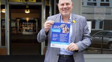 Cllr Tony Dicicco holding a poster to promote the events