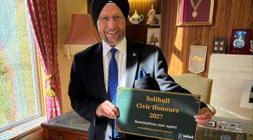 The Mayor of Solihull, Councillor Sardul Singh Marwa MBE JP with a Civic Honours poster