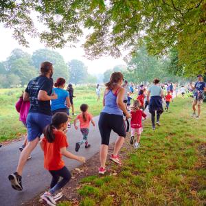 Families running in park while a spectator claps