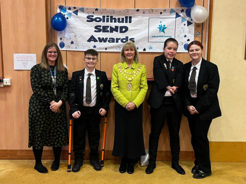 The Mayor stood with three Lode Heath School students and their teacher posing for a photo in front of a Solihull SEND Awards banner.