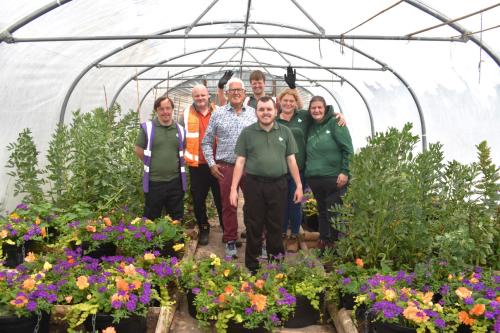 Service users at Newlands Bishop Farm stand in the polytunnel, with Cllr Ken Hawkins and representatives from Veolia and Newlands Bishop Farm