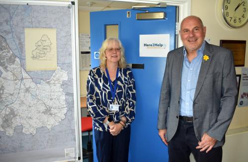 Kerry Turner and Cllr Tony Dicicco stood next to a Here2Help Advice Service sign