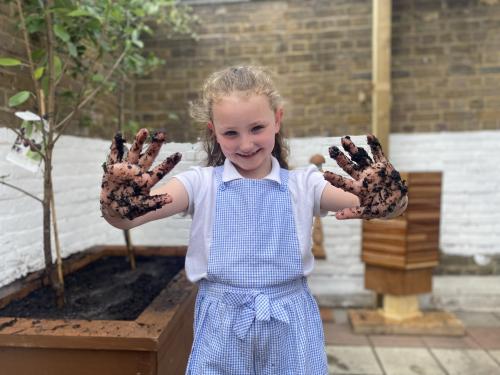 A school girl with muddy hands, promoting the Veolia Orchard scheme